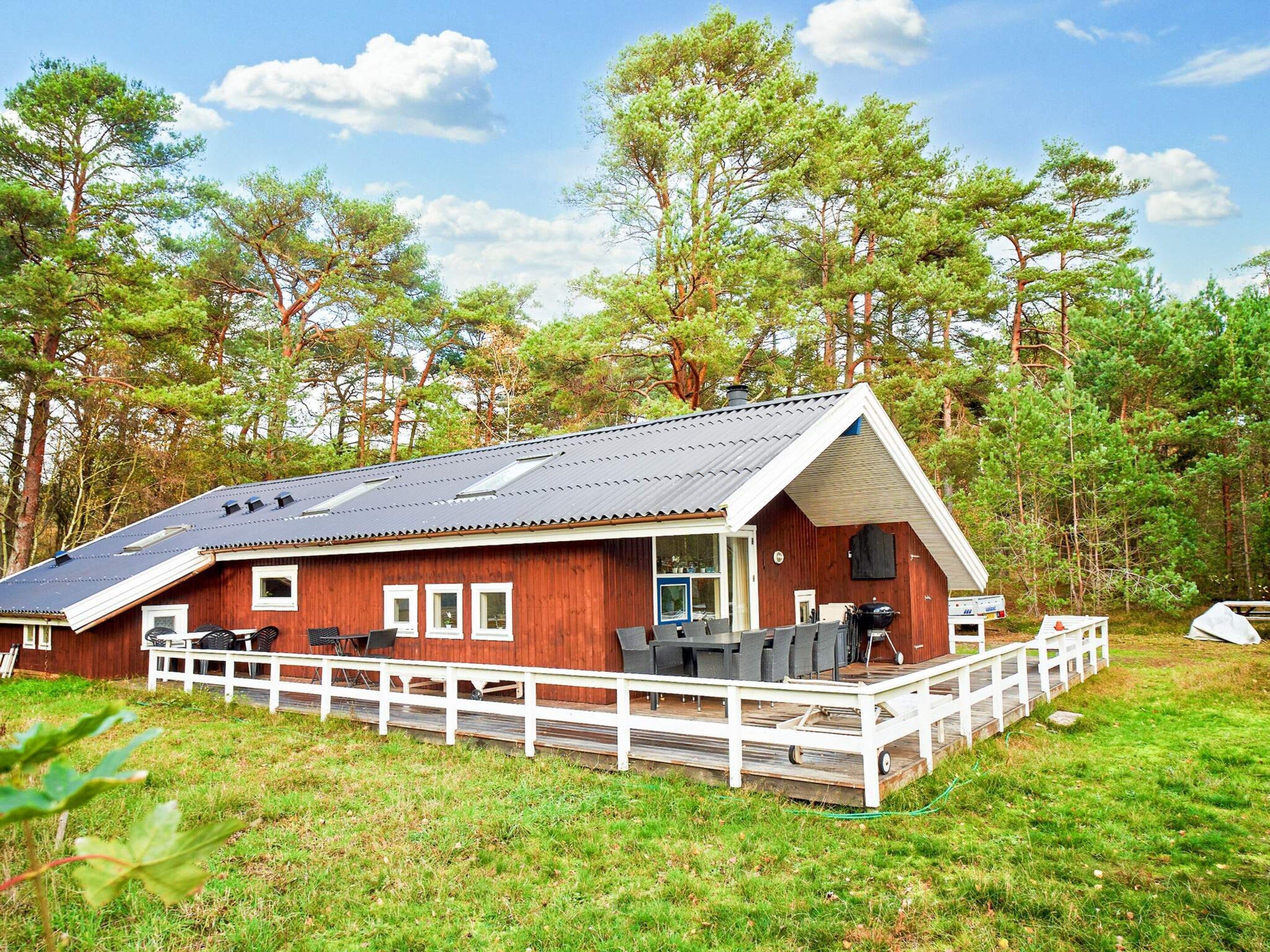A wooden cabin with a porch, outdoor seating, and a grill area.