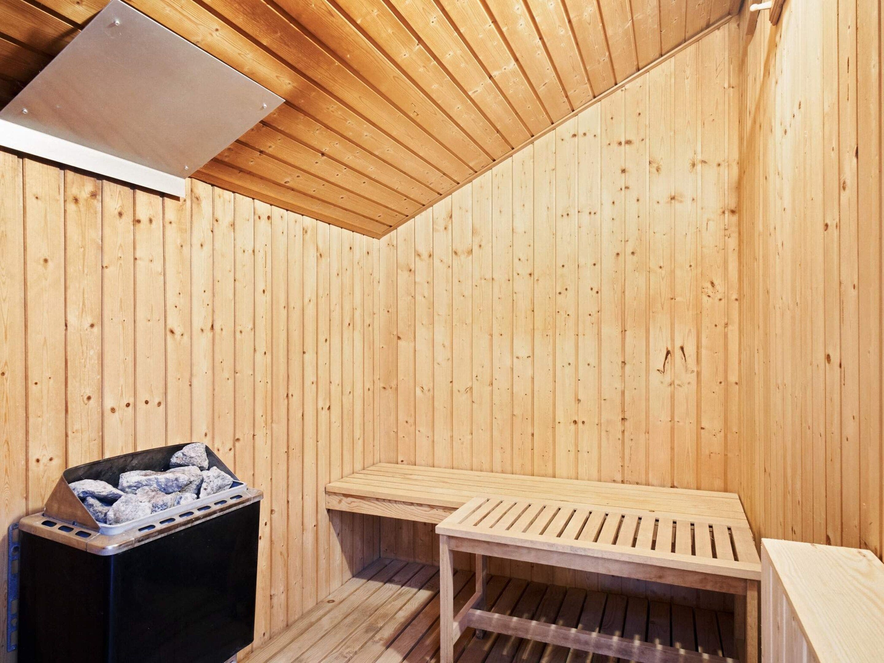 A sauna room with wooden walls and a sloped ceiling.