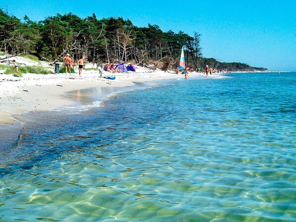 A beach with clear water, tents, and people.
