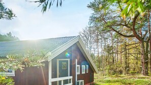 En træhytte med skråt tag, en veranda og en lille aircondition.