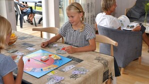 Un grup de persones jugant a un joc de taula amb un tablero de Monopoly i diners.