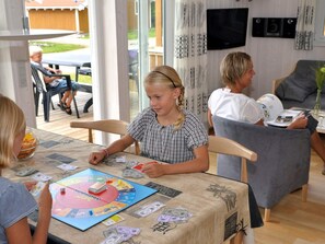 Un groupe de personnes jouant à un jeu de société autour d’une table, avec un plateau de jeu de Monopoly et de l’argent.