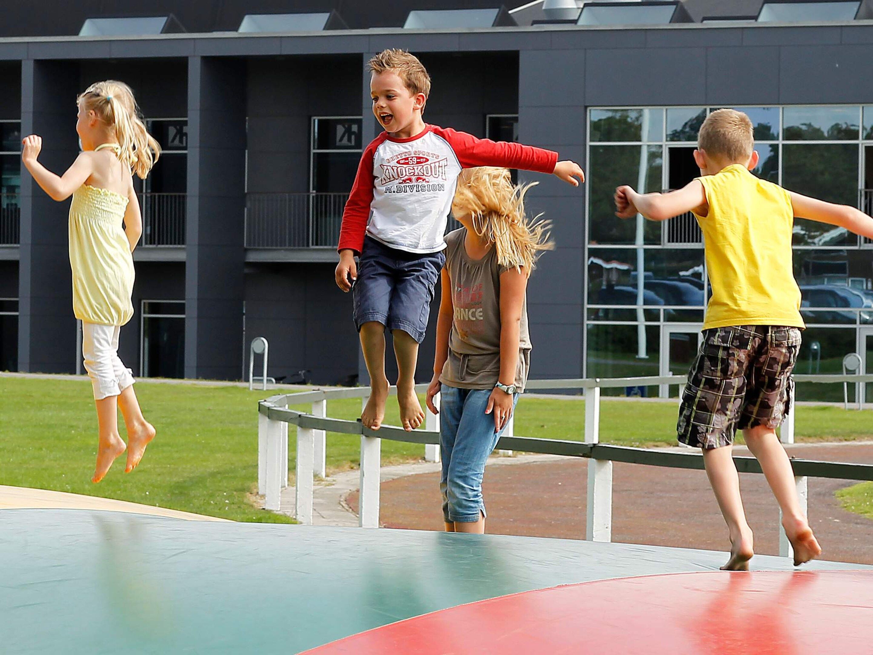 Children playing on an outdoor trampoline.