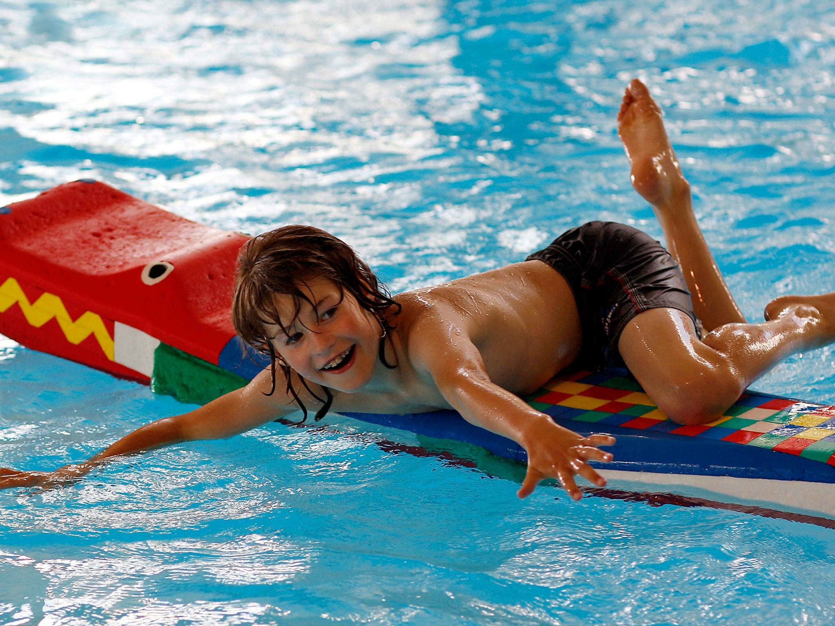 Un enfant dans une piscine, utilisant un flotteur en forme de requin.