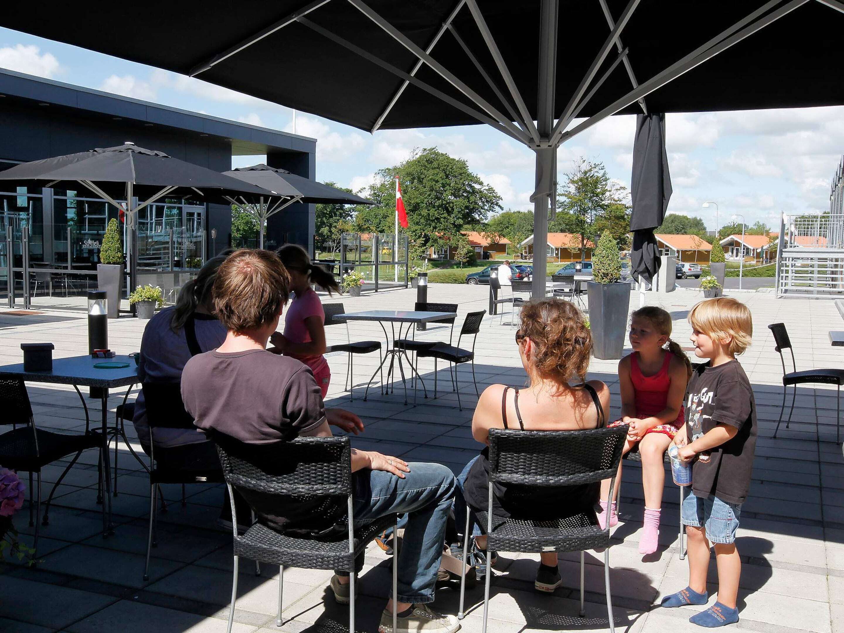 An outdoor seating area with tables and chairs under a shaded structure.