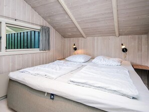 A room with a loft-style ceiling, two beds with white bedding, a window with striped curtains, and two wall-mounted lamps. - 4 Star Holiday Home in Borkop (Borkop)