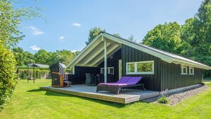A modern cabin with a deck, outdoor seating, and a large window. - 4 Star Holiday Home in Borkop (Borkop)