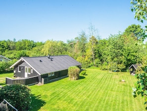 A house with a sloped roof, a well-maintained lawn, and a small shed in the background.