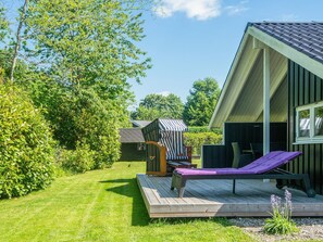 Une terrasse en bois avec un fauteuil de relaxation et un petit espace salon extérieur.