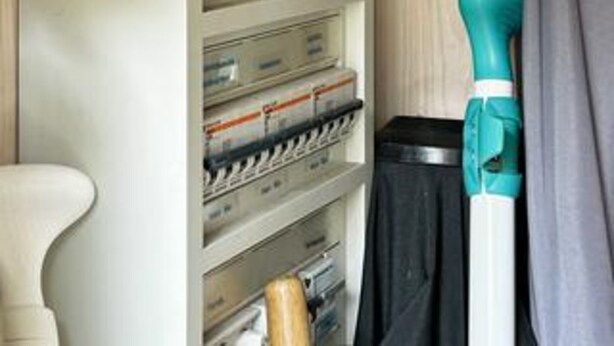 A storage area with shelves containing various items, a black trash bin, and a teal cleaning tool. - 4 Star Holiday Home in Borkop (Borkop)