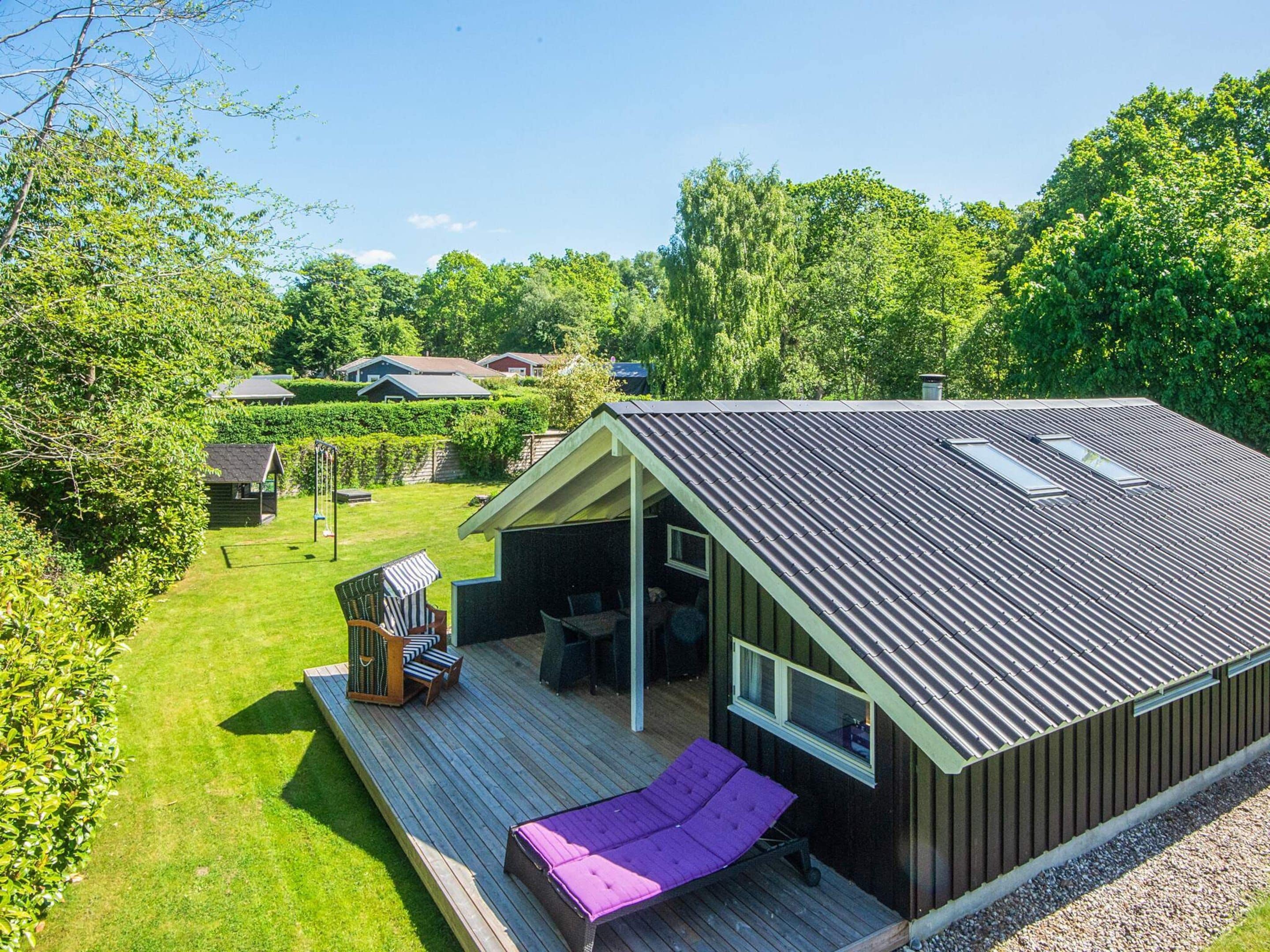 A modern house with a deck, a covered outdoor seating area, and a view of the surrounding greenery.
