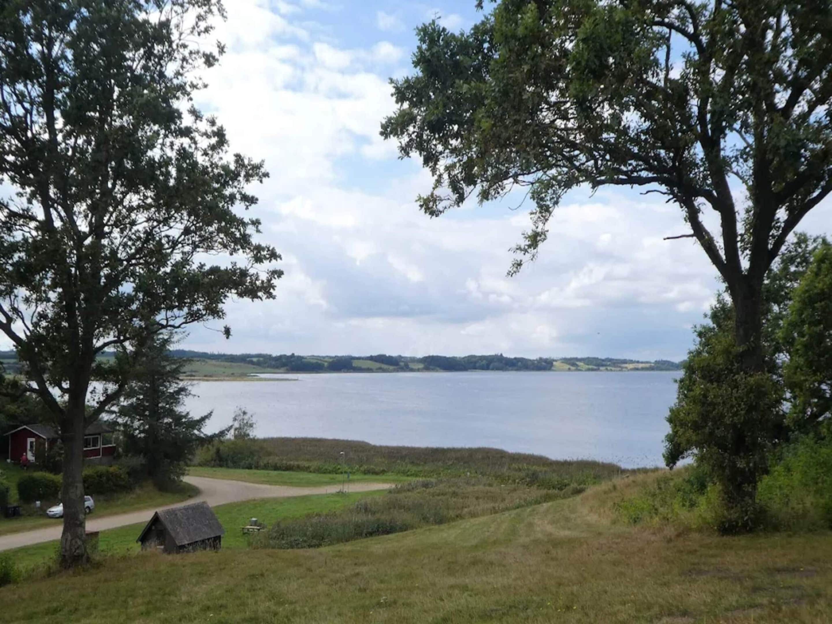 A lakeside property with a house, a small shed, and a grassy area.