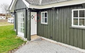 A single-story building with a dark exterior, a white door, and a window. - 8 Person Holiday Home in Logstrup-by Traum (Logstrup)