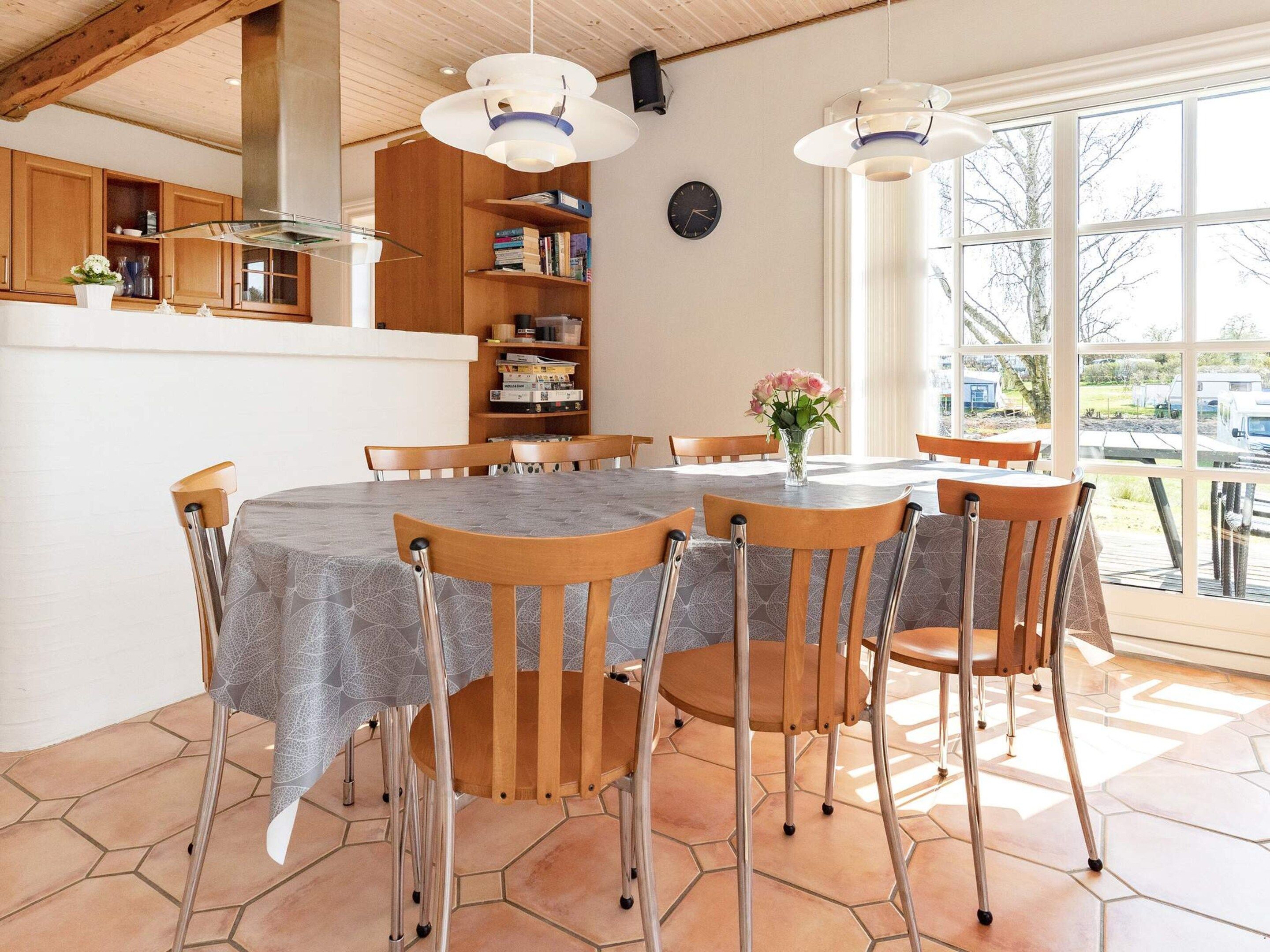 A dining area with a round table, six chairs, and a vase of flowers.