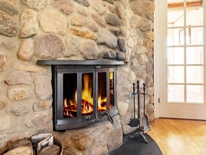 A stone fireplace with a black wood-burning stove, logs, and a chimney. - 5 Star Holiday Home in Logstrup (Logstrup)