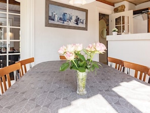 A dining table with a vase of roses, wooden chairs, and a painting on the wall. - 5 Star Holiday Home in Logstrup (Logstrup)