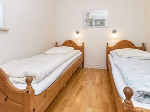 A room with two wooden beds, a white wall, and a framed picture. - 5 Star Holiday Home in Logstrup (Logstrup)