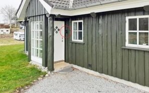 A single-story building with a dark exterior, a white door, and a window. - 5 Star Holiday Home in Logstrup (Logstrup)