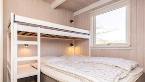 A bunk bed with a ladder, a window with a view, and two wall-mounted lamps.