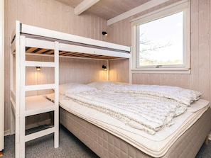A bunk bed with a ladder, a window with a view, and two wall-mounted lamps.