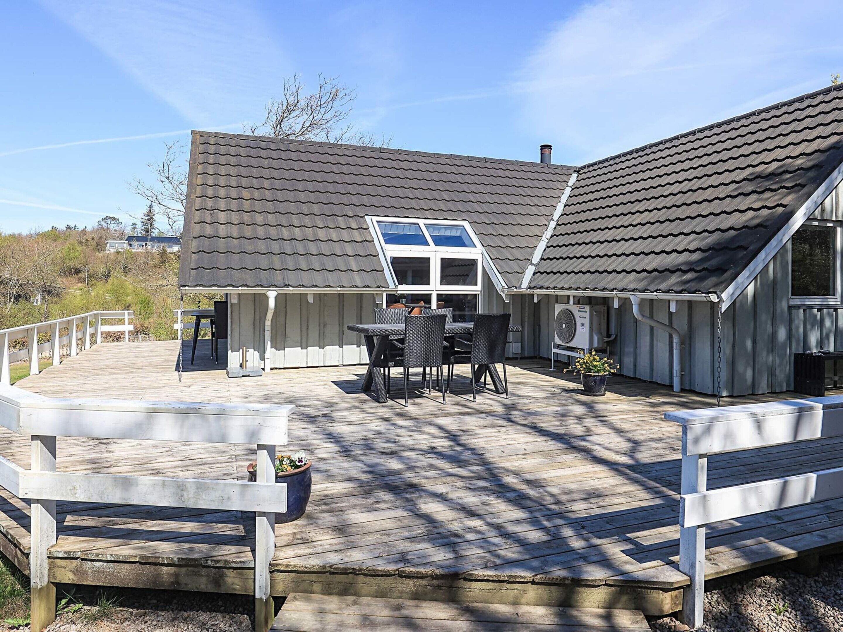 A wooden deck with outdoor furniture, a covered patio area, and a building with a sloped roof.