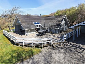 Et toetagers træhus med en terrasse, et spiseområde og et stort vindue.