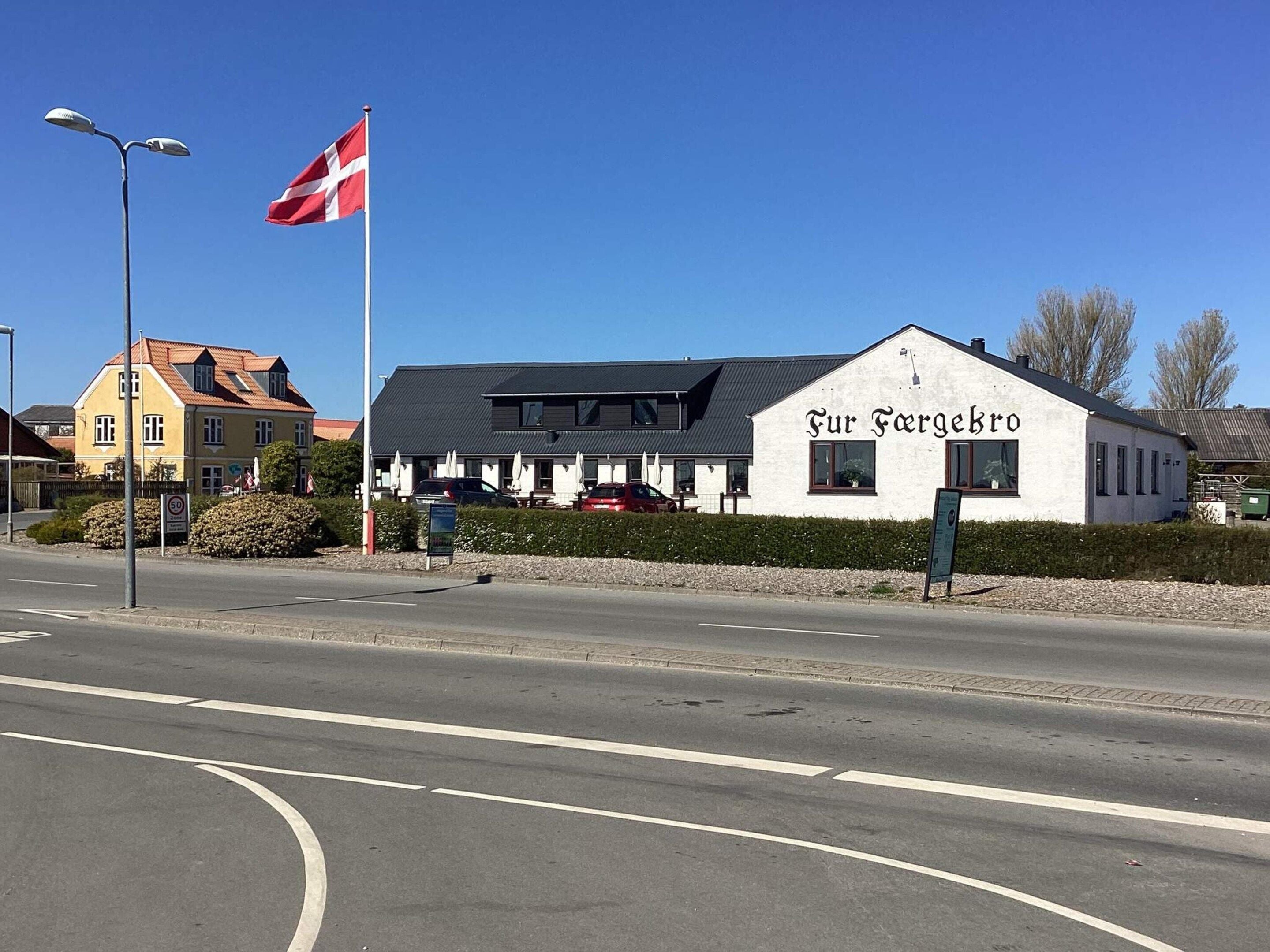 A building with a sign reading 'Fur Forgebro' and a flagpole with a flag.