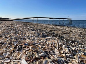 A beach with a pier extending into the water, covered in shells. - Swanky Seaside Holiday Home in Fur near Sea (Fur)