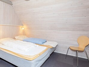 A single bed with a wooden headboard, a bedside lamp, and a chair. - Swanky Seaside Holiday Home in Fur near Sea (Fur)