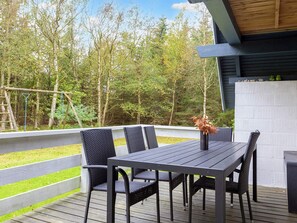 An outdoor deck with a table and chairs, surrounded by a wooden deck and a view of trees. - Swanky Seaside Holiday Home in Fur near Sea (Fur)