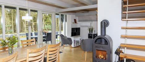 Een modern interieur met een eethoek, een open haard en uitzicht door grote ramen.