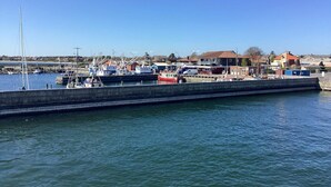 A marina with boats docked, a concrete breakwater, and buildings in the background. - Swanky Seaside Holiday Home in Fur near Sea (Fur)