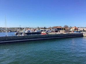 A marina with boats docked, a concrete breakwater, and buildings in the background. - Swanky Seaside Holiday Home in Fur near Sea (Fur)