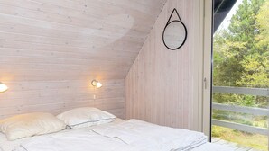 A bedroom with a bed, two wall-mounted lights, and a window with a view of trees. - Swanky Seaside Holiday Home in Fur near Sea (Fur)