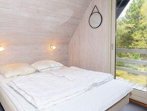 A bedroom with a bed, two wall-mounted lights, and a window with a view of trees. - Swanky Seaside Holiday Home in Fur near Sea (Fur)