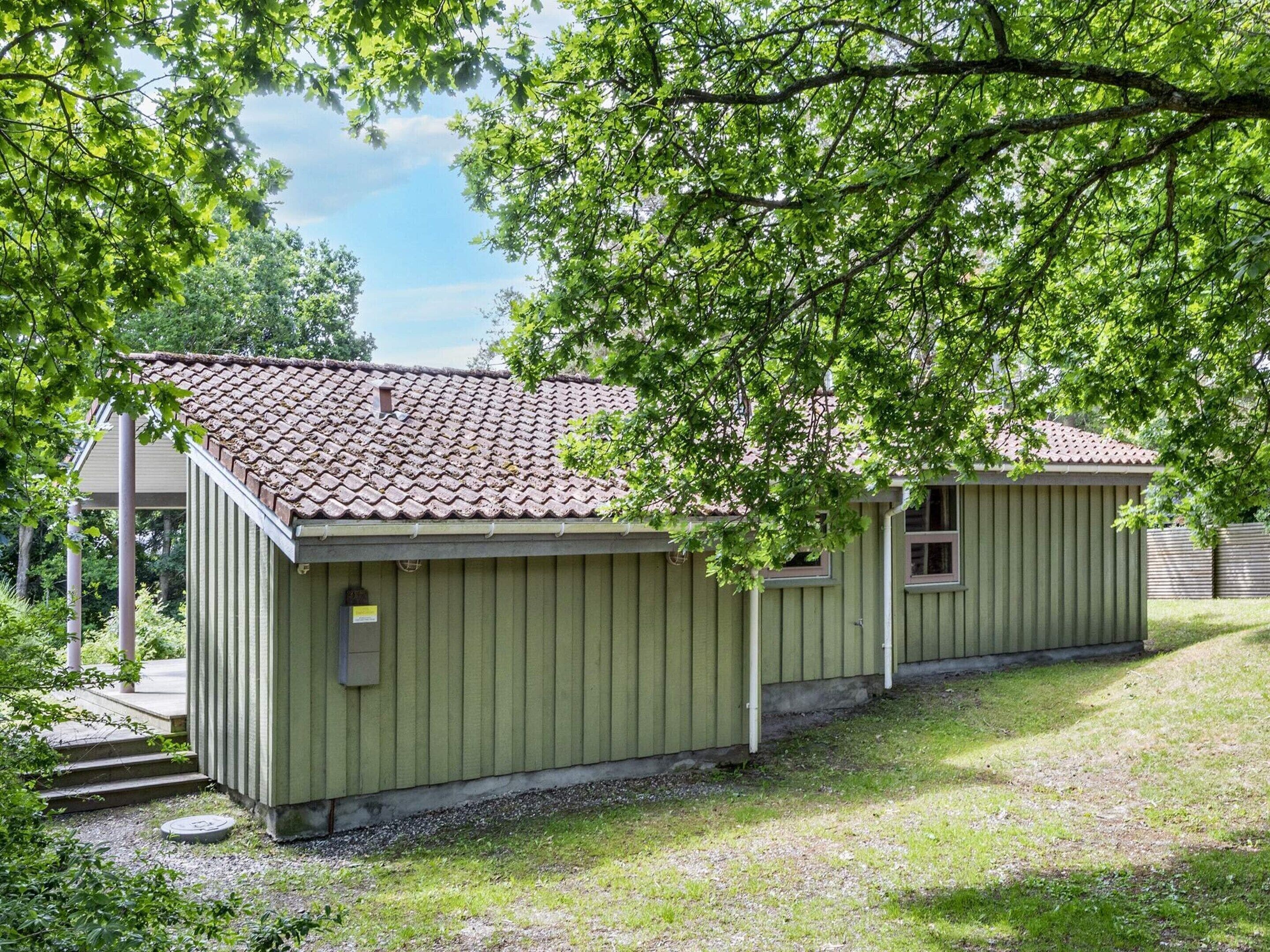 A small, single-story building with a tiled roof and a green exterior.