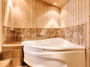 A bathroom with a freestanding bathtub, tiled walls, and wooden paneling.
