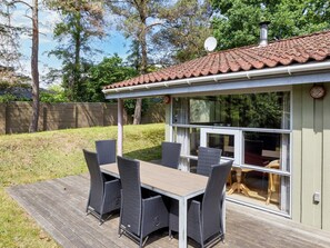 A covered patio area with a table and chairs, a window, and a satellite dish.