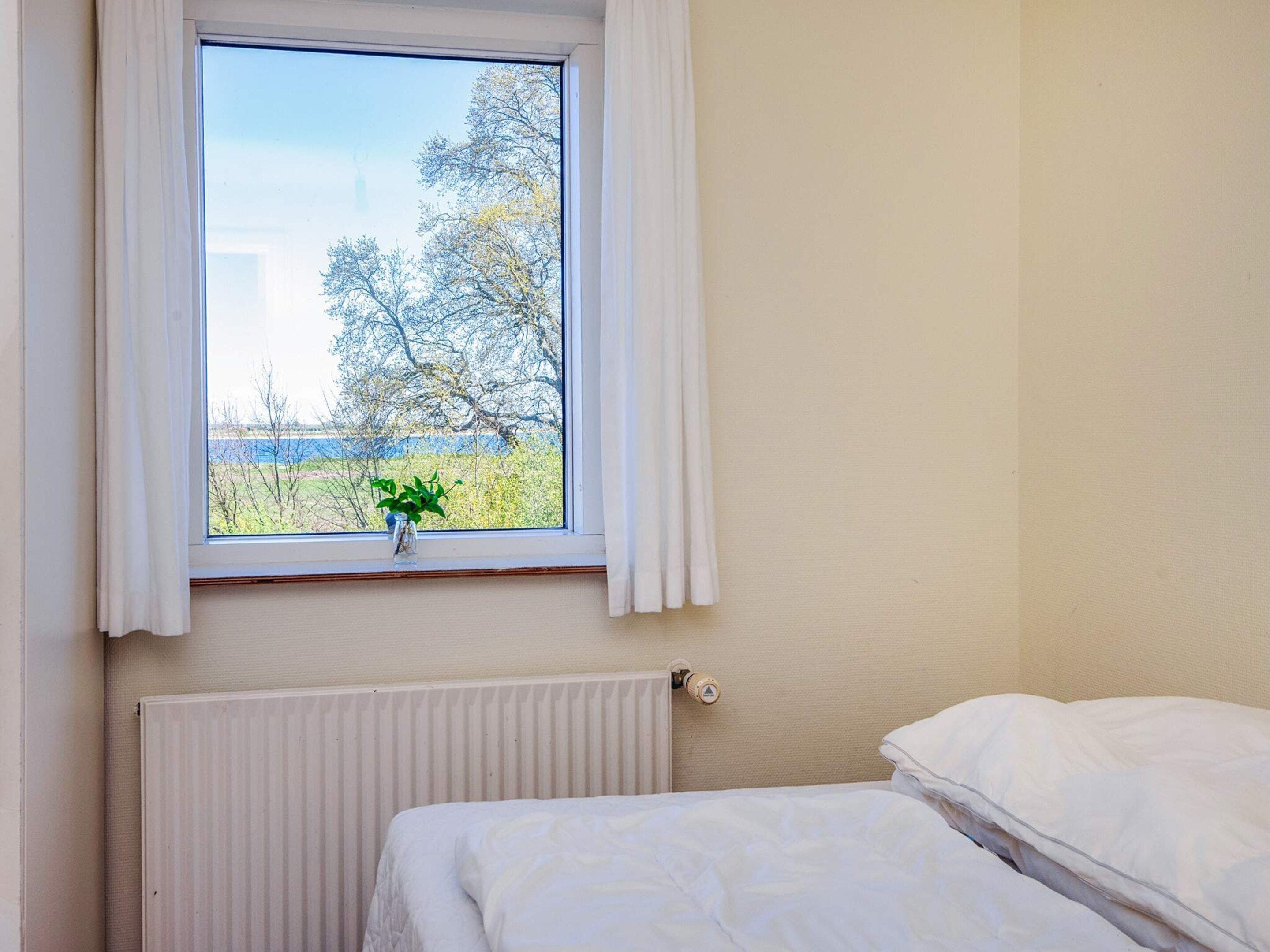 A bedroom with a window, a radiator, and a bed.