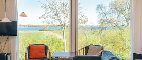 A room with a large window, a leather sofa, a table, and a chair.