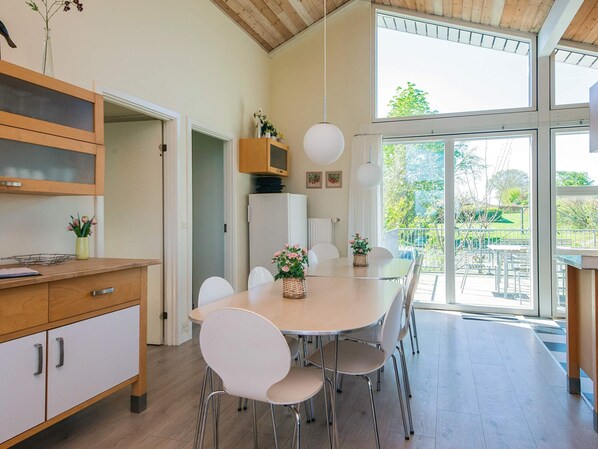 A modern kitchen with white cabinets, a wooden countertop, and a dining area with a round table and white chairs.
