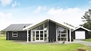 A modern two-story house with a large glass front, a garage, and a well-maintained lawn. - 5 Star Holiday Home in Hjorring (Hjørring)