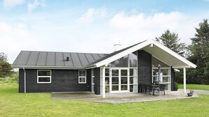 A modern house with a large garage, a covered patio with outdoor furniture, and a well-maintained lawn. - 5 Star Holiday Home in Hjorring (Hjørring)