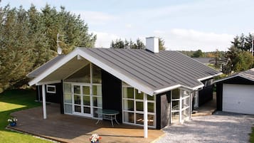 Une maison moderne avec un toit en pente, de grandes fenêtres et un patio couvert.