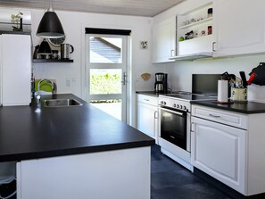 A modern kitchen with white cabinetry, a black countertop, a Bosch oven, and a coffee maker. - Alluring Holiday Home in Hadsund near Sea (Hadsund)