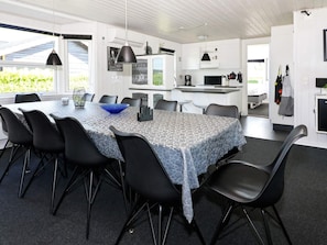 Une cuisine moderne avec des meubles blancs, un plan de travail noir et un luminaire suspendu.