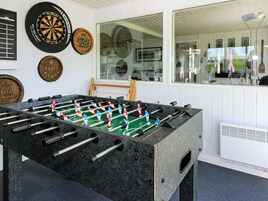 Una mesa de fútbolín en una sala con dardos colgados en la pared.