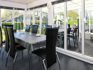 A sunlit room with a table and chairs, large windows, and a view of the outdoors. - Alluring Holiday Home in Hadsund near Sea (Hadsund)