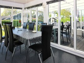 Una habitación iluminada por el sol, con una mesa y sillas, ventanas amplias y vistas al exterior.