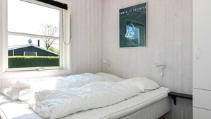 A single-bed room with a window, a poster on the wall, and a bedside table.